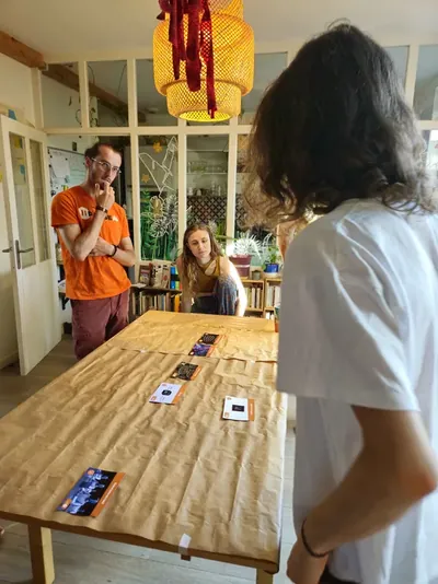 L'animateur explique une carte à deux participant·es, au début de l'atelier.