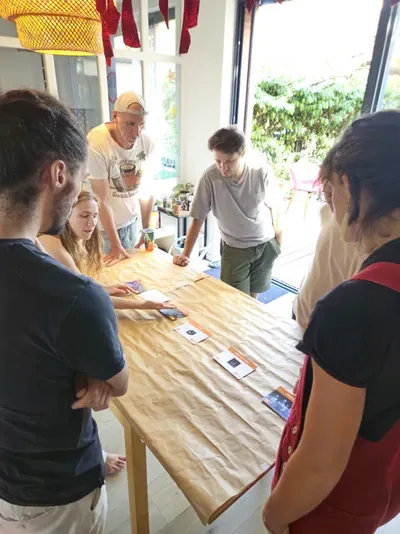 Un groupe échange autour de la table pendant que deux personnes placent une carte.